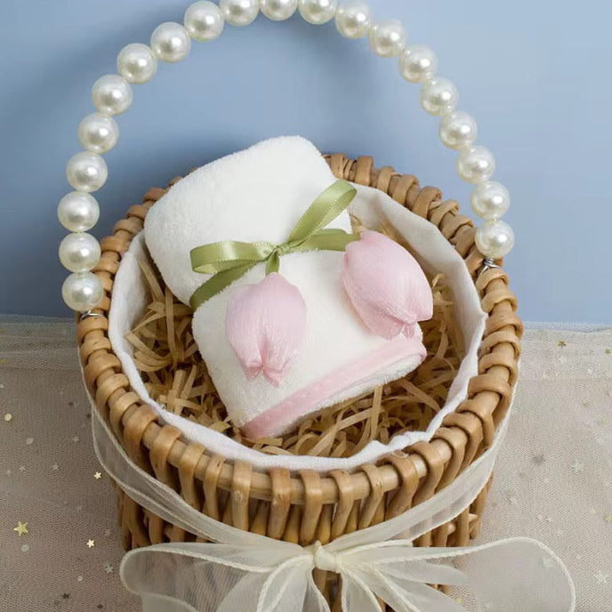 Woven basket with a white towel, pink flowers, and a pearl handle on a light blue background.